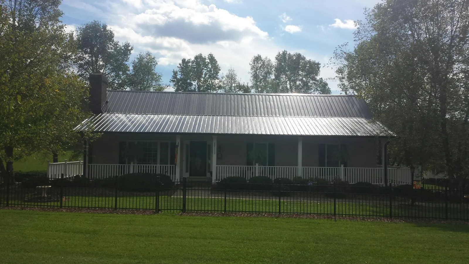 Gray metal roof on a brick ranch with a full width front porch — Gutter Guard Installation work by our crew in Morris